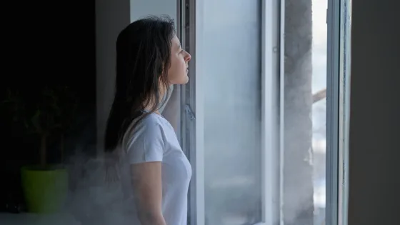 Une femme ouvre une fenetre et la condensation s echappe a l exterieur