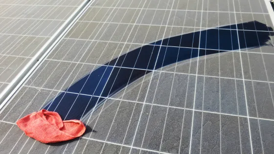 Un panneau solaire très encrasse par la poussiere avec un chiffon mouille sur la vitre